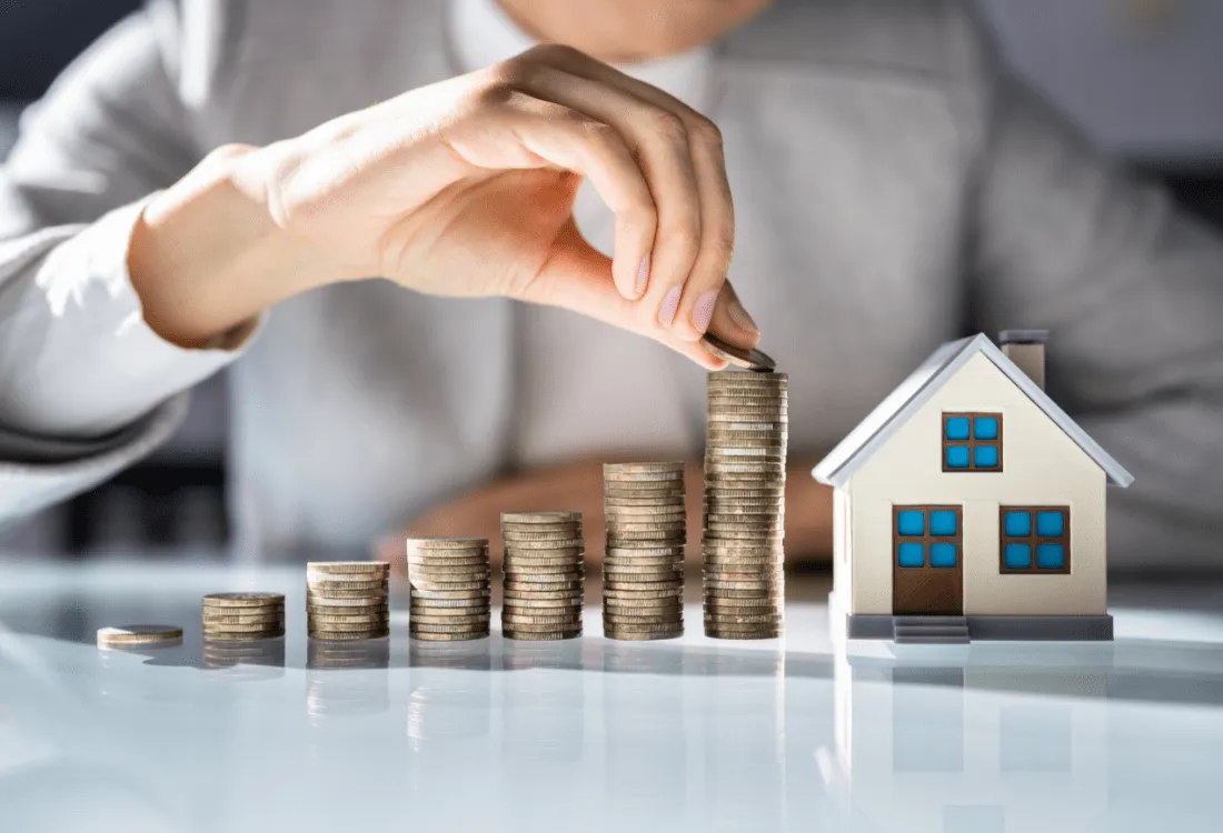 Stacked coins increasing in height next to a small model house, representing property management fees and landlord income – illustrating the cost of letting agent services and how much do letting agents charge to manage a property.